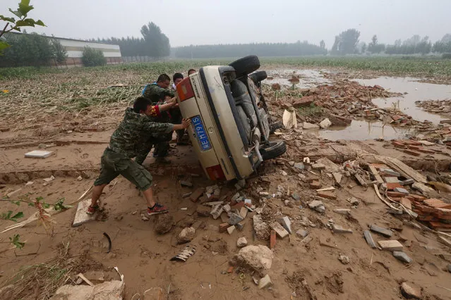 People push a car turned over during floods in Xingtai, Hebei Province, China, July, 24, 2016. (Photo by Reuters/Stringer)
