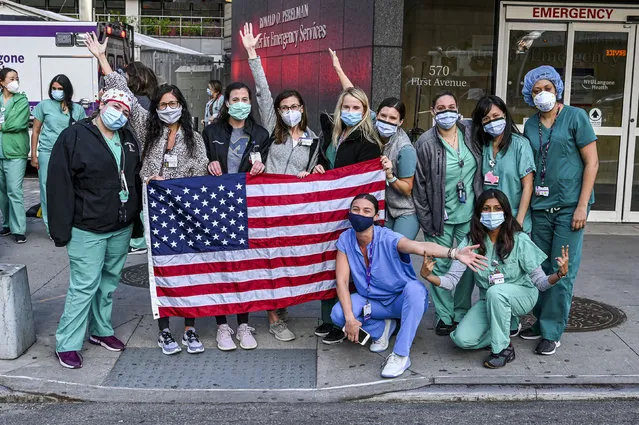 Medical workers hold up an American Flag outside NYU Langone Health hospital as people applaud to show their gratitude to medical staff and essential workers during the coronavirus pandemic during the COVID-19 pandemic on May 07, 2020 in New York City. COVID-19 has spread to most countries around the world, claiming over 270,000 lives with infections over 3.9 million people. (Photo by Ben Gabbe/Getty Images)