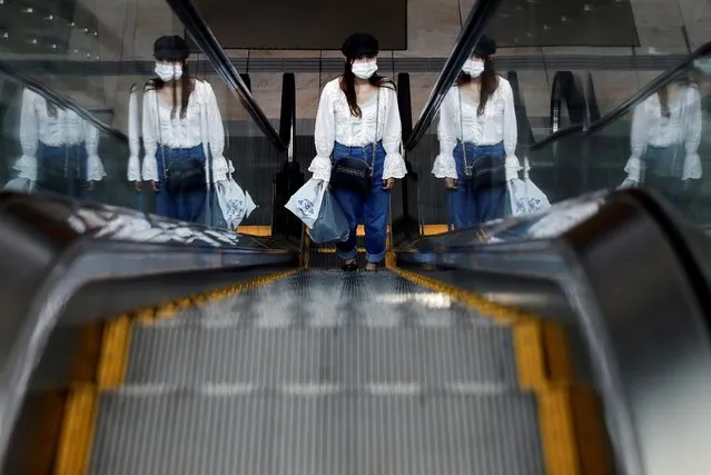A woman wearing a protective face mask uses an escalator in a quiet business district on the first working day after the Golden Week holiday, following the coronavirus disease (COVID-19) outbreak, in Tokyo, Japan, May 7,2020. (Photo by Kim Kyung-Hoon/Reuters)