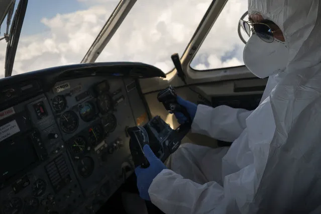 A pilot wearing personal protective equipment airlifts COVID-19 patients from Santo Antonio do Içá to a hospital in Manaus, Brazil, Tuesday, May 19, 2020. (Photo by Felipe Dana/AP Photo)