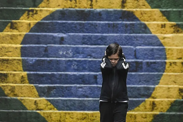 A child heading to school, holds his hands over his ears so as not to hear his mother yelling after him for forgetting his backpack, in the Saude neighborhood of Rio de Janeiro, Brazil, Thursday, September 29, 2022. (Photo by Matias Delacroix/AP Photo)