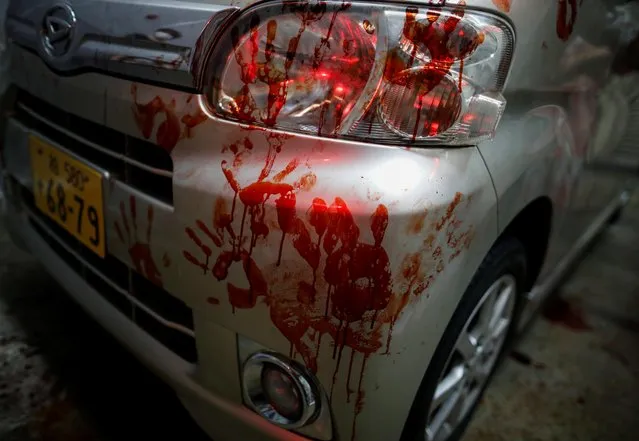 Bloody hand prints are seen on the surface of a car after a drive-in haunted house show, performed by Kowagarasetai (Scare Squad), for people inside a car in order to maintain social distancing amid the spread of the coronavirus disease (COVID-19), at a garage in Tokyo, Japan on July 3, 2020. (Photo by Issei Kato/Reuters)