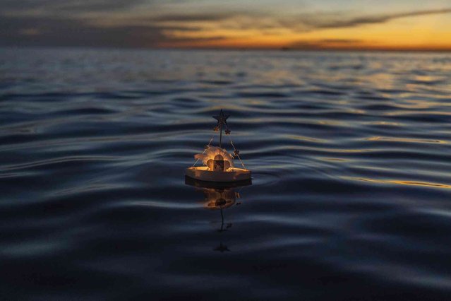 A miniature boat in honor of the African sea goddess Yemanja floats in the waters of Ramirez beach in Montevideo, Uruguay, Friday, February 2, 2024. Worshippers visit the beach on Yemanja's feast day, bearing candles, flowers, honey and fruit to honor the deity. (Photo by Matilde Campodonico/AP Photo)
