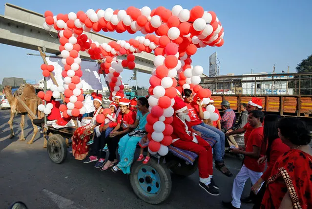 Participants wearing Santa Claus caps ride a camel cart during a parade as part of Christmas celebrations in Ahmedabad, India, December 23, 2017. (Photo by Amit Dave/Reuters)