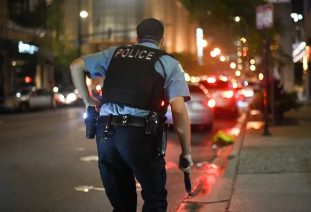 A Chicago Police Officer runs toward gunfire as looters break into downtown stores in the early hours of the morning on August 10, 2020. (Photo by RMV/Rex Features/Shutterstock)