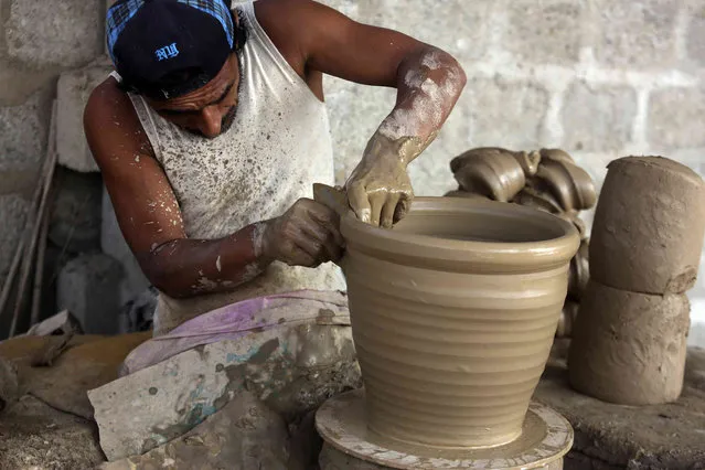 A potter makes a clay pot at his workshop in Karachi, Pakistan, Tuesday, November 8, 2022. (Photo by Fareed Khan/AP Photo)