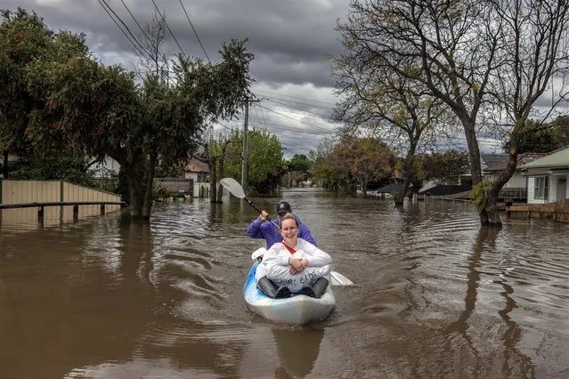 Two residents canoe down a flooded street in the suburb of Maribyrnong on October 14, 2022 in Victoria, Australia. An emergency warning was issued for Maribyrnong this morning with residents near the river told to evacuate homes as flood waters rise following heavy rain. (Photo by Asanka Ratnayake/Getty Images)