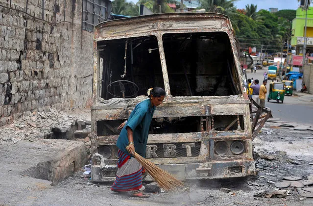 A municipal worker sweeps around the charred remains of a lorry set ablaze during the violent protests after India's Supreme Court ordered Karnataka state to release water from the Cauvery river to the neighboring state of Tamil Nadu, in Bengaluru, India, September 14, 2016. (Photo by Abhishek N. Chinnappa/Reuters)