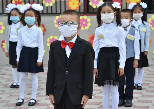 Kyrgyz schoolchildren wearing a protective mask to prevent the spread of the novel coronavirus (covid-19) and keeping a social distance of 1.5 meters stand in lined up at the school before classes in Bishkek on September 1, 2020. Only first graders in Kyrgyzstan will study at school from September 1, the rest of the classes will have online education from home. (Photo by Vyacheslav Oseledko/AFP Photo)