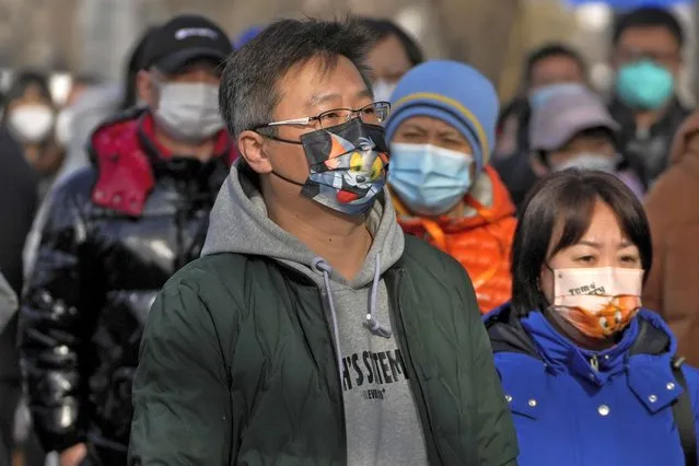 People wearing face masks walk on street in Beijing, Friday, January 6, 2023. (Photo by Andy Wong/AP Photo)