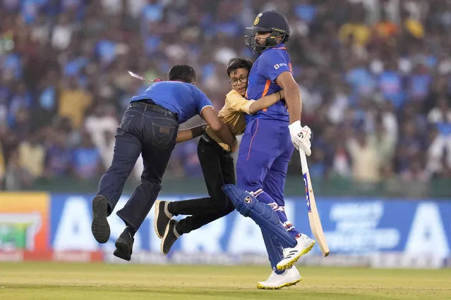 A security guard tries to separate a boy who hugs India's captain Rohit Sharma, right, after invading the field of play during the second one-day international cricket match between India and New Zealand in Raipur, India, Saturday, January 21, 2023. (Photo by Aijaz Rahi/AP Photo)