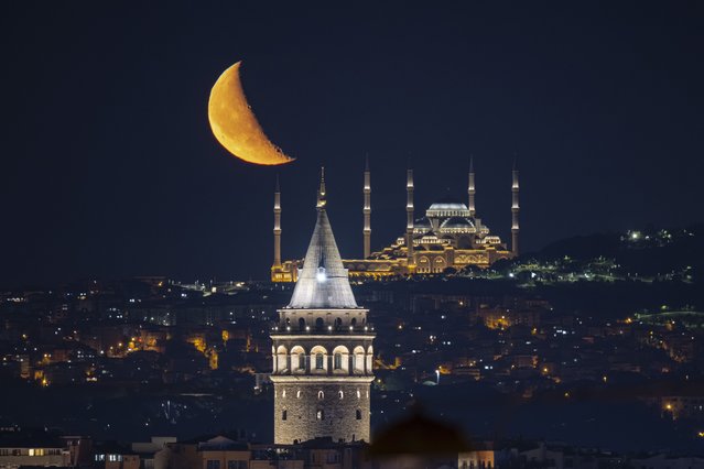 Half Moon is seen with Grand Camlica Mosque and Galata Tower during night time in Istanbul, Turkiye on June 20, 2025. (Photo by Isa Terli/Anadolu via Getty Images)