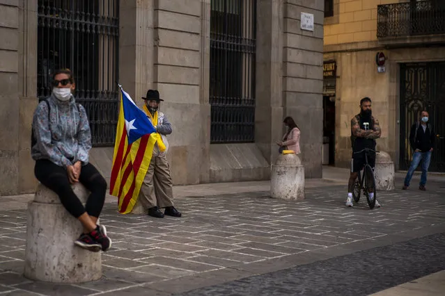 A man holding an “estelada” or independence flag waits for a protest to condemn a police raid on Catalan separatists in Barcelona, Spain, Wednesday, October 28, 2020. Spanish officials say that police have arrested 21 individuals with links to the Catalan separatist movement on suspicion of corruption and promoting public disorder. (Photo by Emilio Morenatti/AP Photo)