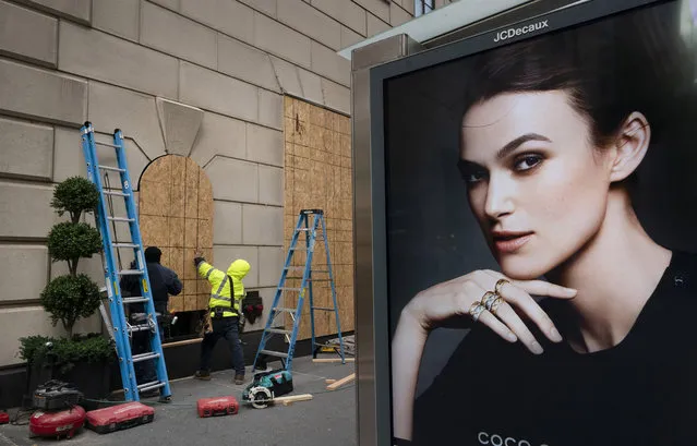 Workers board up Bergdorf Goodman department store, Monday, November 2, 2020, in New York ahead of Tuesday's contentious presidential election. The moves come as retailers are trying to protect themselves against possible civil unrest in a year that has seen widespread protests over social justice that sometimes became violent. (Photo by Mark Lennihan/AP Photo)