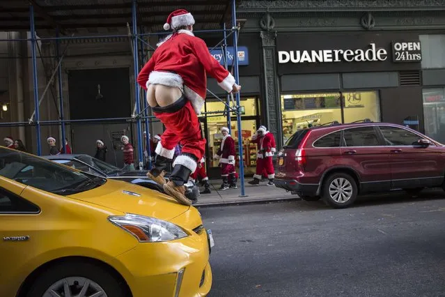 A drunken reveler jumps on a taxi with his pants down as he takes part in SantaCon through Midtown Manhattan, New York  December 13, 2014. Waves of revelers dressed in Santa Claus outfits invaded Midtown Manhattan on Saturday as part of New York's version of SantaCon, a massive pub crawl that organizers scaled back this year in part to prevent conflicts with a nearby protest march. (Photo by Elizabeth Shafiroff/Reuters)