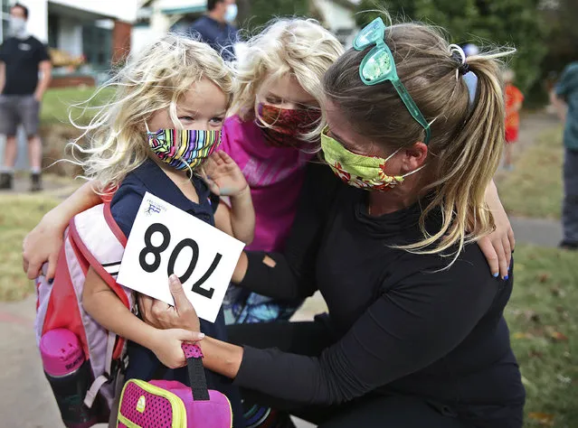 Beatrice James,5, left, is greeted by her sister Claudia, 7, and mother Sarah after her first day of pre-kindergarten at Council Oak Elementary School in Tulsa, Okla., Monday, November 9, 2020. Tulsa Public School returned to in-person instruction for kindergartners and pre-kindergartners on Monday, amid the coronavirus pandemic. (Photo by Mike Simons/Tulsa World via AP Photo)