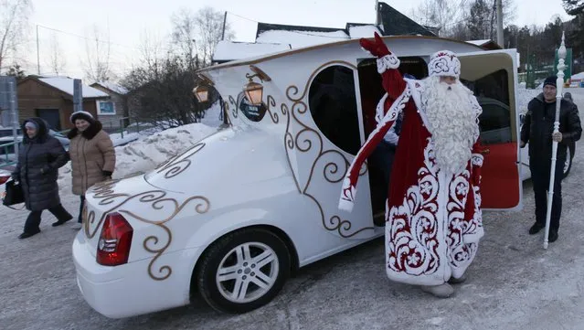 A man dressed as Father Frost, Russian equivalent of Santa Claus, welcomes people as he leaves a car during a children's celebration at Father Frost's forest residence set up inside a local zoo in the Taiga district, outside Krasnoyarsk, Siberia, December 20, 2014. Russia's main Father Frost from Veliky Ustyug visited Krasnoyarsk on Saturday, according to local media and the event organizers. (Photo by Ilya Naymushin/Reuters)