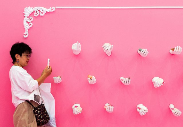 A woman takes a photo of sculpted hands holding pieces of soap at the JD Global Soap Museum, part of the 798 Art District in Beijing, China on October 7, 2025. (Photo by Maxim Shemetov/Reuters)