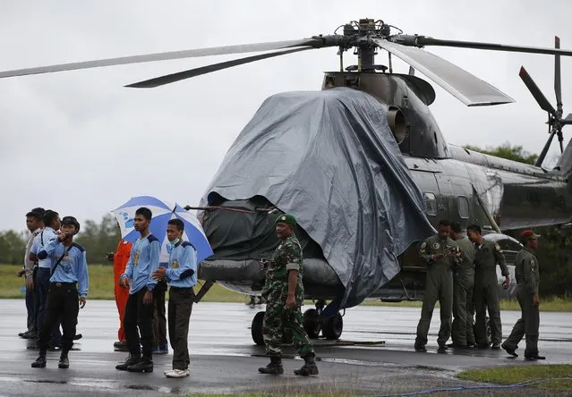 An Indonesian military helicopter, used in recovery efforts for the missing AirAsia plane, sits idle on the tarmac at Iskandar Airport during bad weather in Pangkalan Bun, Central Kalimantan, December 31, 2014. (Photo by Darren Whiteside/Reuters)