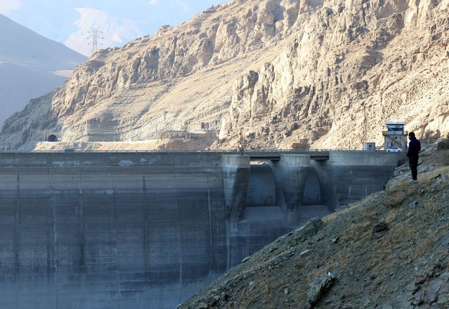 An Iranian man stands at an area overlooking the Amir-Kabir dam (Karaj dam) running at low capacity in the Karaj river in Alborz province, northern Iran, 10 November 2025. According to Iran Water Resource Management, less than 10 percent of the dam's capacity is full, while 67 percent of dams across Iran are empty, reflecting a severe drought crisis caused by low rain and snowfall. (Photo by Abedin Taherkenareh/EPA)