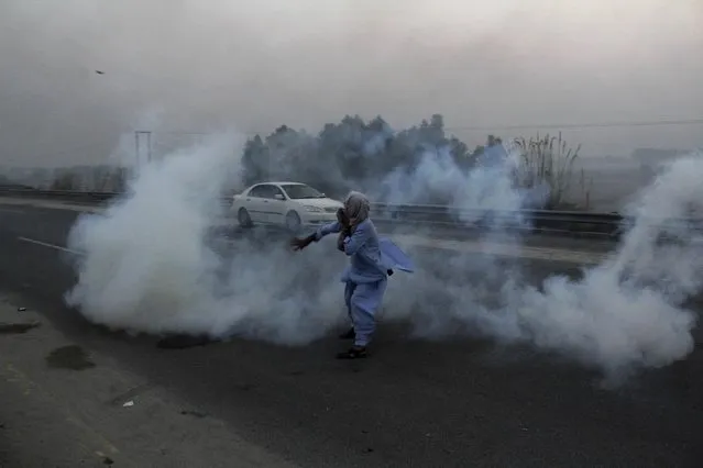 A supporter of Imran Khan's Pakistan Tehreek-e-Insaf party, throws a teargas shell towards police during a clash in Hazro, Pakistan, Monday, October 31, 2016. Pakistani police launched a nation-wide crackdown overnight, arresting at least 1,500 supporters of Khan ahead of an opposition rally planned later this week in Islamabad, officials said Monday. (Photo by Mohammad Sajjad/AP Photo)