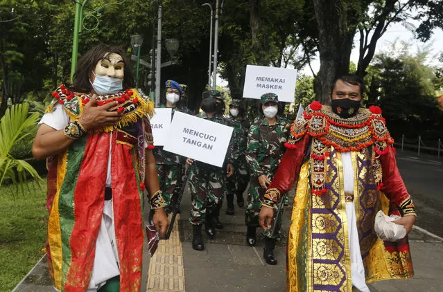Indonesian military officers wear traditional Balinese costume calling for people to always have their mask and wash hands to prevent the spread of coronavirus outbreak on a street in Bali, Indonesia on Monday, January 11, 2021. (Photo by Firdia Lisnawati/AP Photo)