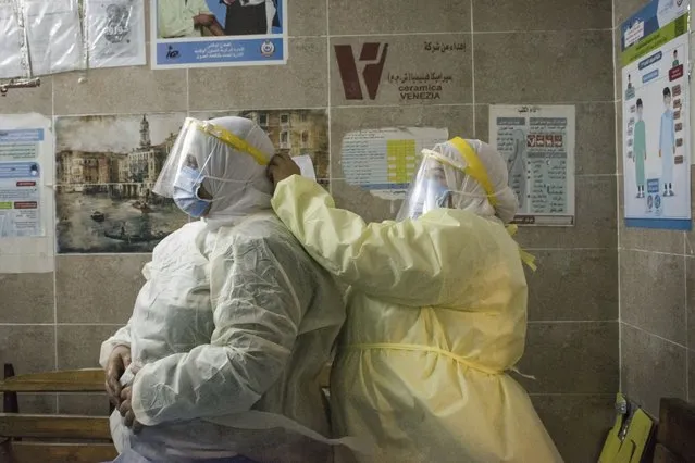 A nurse helps a colleague to put on her personal protective equipment at the 6th of October Central Hospital, which is currently serving as an isolation hospital for coronavirus (COVID-19) patients in Giza, Egypt on July 7, 2020. Photo by Menna Hossam/picture alliance via Getty Images)
