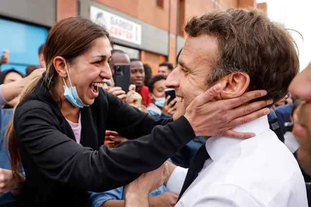 French incumbent president and candidate of La Republique en Marche (LREM) party for the presidential election Emmanuel Macron (R) greets an inhabitant during a campaign visit in the “Fontaine d'Ouche” neighborhood in Dijon, on March 28, 2022. (Photo by Ludovic Marin/AFP Photo)