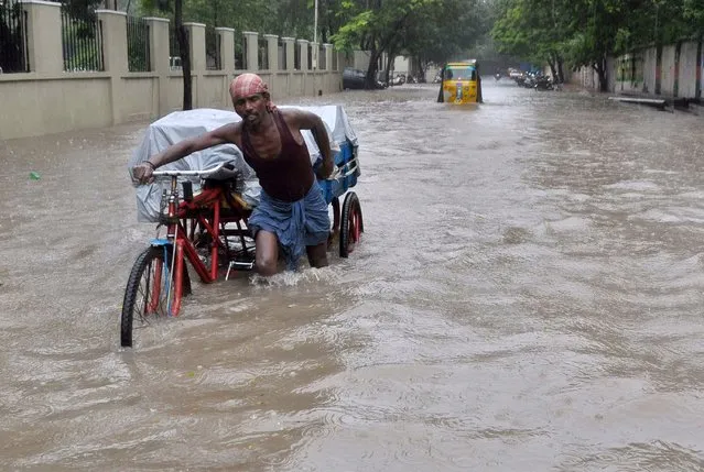 An Indian labourer pushes his cycle trishaw through floodwaters in Chennai on December 1, 2015, during a downpour of heavy rain in the southern Indian city. Heavy rains pounded several parts of the southern Indian state of Tamil Nadu and inundating most areas of Chennai, severely disrupting flights, train and bus services and forcing the postponment of half-yearly school exams. (Photo by AFP Photo/Stringer)