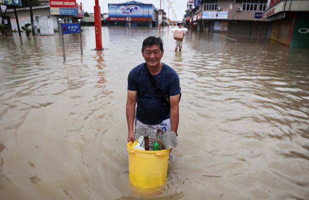Men wade through floodwater carrying their belongings after heavy rain in the northern states of Malaysia, bordering Thailand, in Kangar, Malaysia on November 26, 2025. (Photo by Hasnoor Hussain/Reuters)
