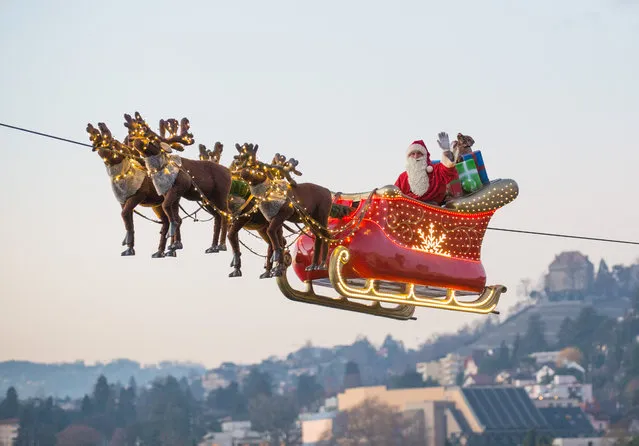 Santa waves to a crowd from his flying sleigh in Montreux, Switzerland on December 7, 2015. (Photo by Xinhua/Barcroft Media)