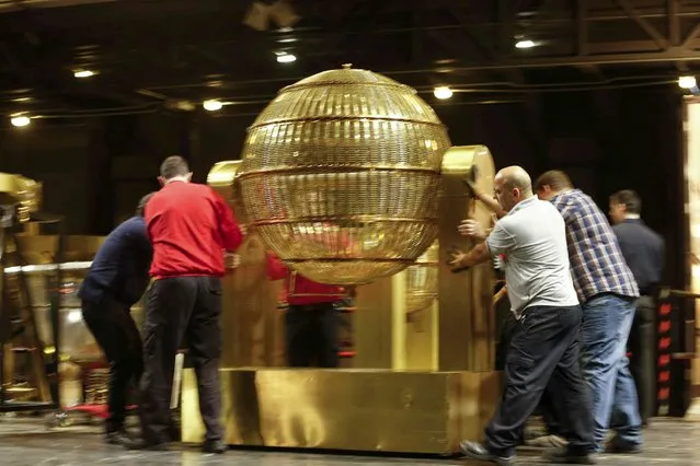Workers move one of the drawing spheres, which will be used for the  Christmas Lottery draw on 22 December, as it is set up at the Royal Opera House, in Madrid, Spain, 14 December 2015. The traditional Spanish Christmas Lottery “El Gordo” (The Fat One) will share out a total of 2.24 billion euros that will be divided in 24,486,400 prizes. The main prize per ticket are 400,000 euros for the first prize; 125,000 for the second; 50,000 for the third; 20,000 for the fourth; and 6,000 for the fifth. Photo by Juan Carlos Hidalgo/EPA)