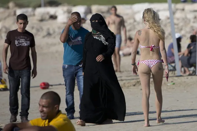 Palestinians and Israelis enjoy the Mediterranean sea during the first day of the Eid al-Fitr holiday in Tel Aviv, Israel, Thursday, August 8, 2013. The three-day Eid al-Fitr holiday marks the end of the holy fasting month of Ramadan. One of the most important holidays in the Muslim world, Eid al-Fitr, is marked with prayers, family reunions and other festivities. (Photo by Oded Balilty/AP Photo)