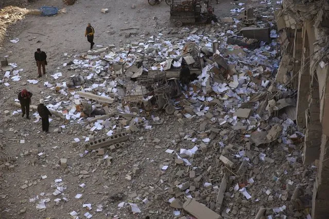 Residents walk amidst scattered copybooks in a site damaged from what activists said was shelling by forces loyal to Syria's President Bashar al-Assad in the town of Douma, eastern Ghouta in Damascus, Syria December 30, 2015. (Photo by Bassam Khabieh/Reuters)