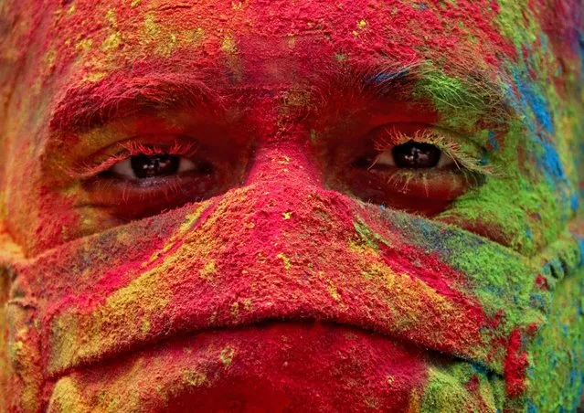 A man wearing a protective face mask daubed in looks on during Holi celebrations, amidst the spread of the coronavirus disease (COVID-19), in Mumbai, India, March 29, 2021. (Photo by Niharika Kulkarni/Reuters)
