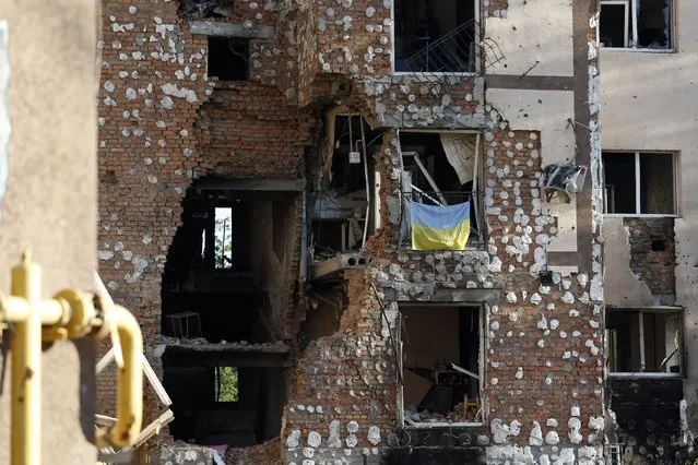 The Ukrainian flag is visible on a window of a destroyed house that was damaged as a result of the shelling of the Russian army in the city of Irpin, near the Ukrainian capital Kyiv on May 16, 2022. Russia invaded Ukraine on 24 February 2022, triggering the largest military attack in Europe since World War II. (Photo by Sergei Chuzavkov/SOPA Images/LightRocket via Getty Images)
