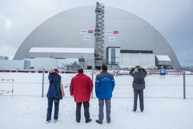 People take pictures following a ceremony to mark the movement of the New Safe Confinement sarcophagus over the destroyed reactor number four at the Chernobyl nuclear power station on November 29, 2016 in Chernobyl, Ukraine. On April 26, 1986 workers at the Chernobyl nuclear power plant inadvertantly caused a meltdown in reactor number four, causing it to explode and send a toxic cocktail of radioactive fallout into the atmosphere in the world's worst civilian nuclear incident. (Photo by Brendan Hoffman/Getty Images)
