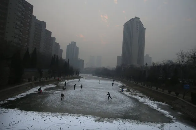 Residents skate and play ice hockey on a frozen river amid heavy smog during winter in Beijing, China, December 29, 2015. (Photo by Jason Lee/Reuters)
