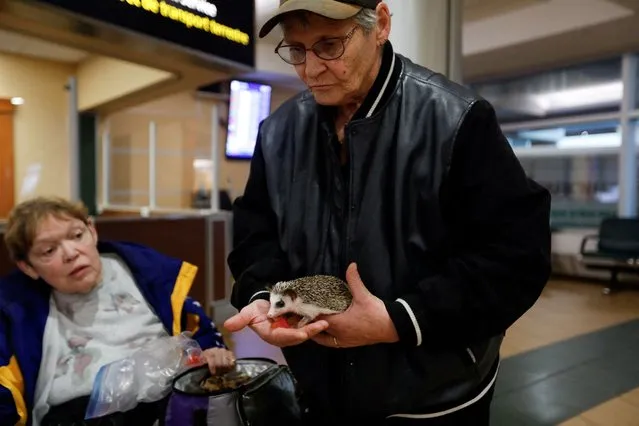 Audrey Henderson holds her hedgehog Dome after arriving with other evacuees, as wildfires threaten the Northwest Territories town of Yellowknife at the airport in Edmonton, Alberta, Canada on August 17, 2023. Henderson had originally booked the trip for scheduled medical appointments but brought her pet along in consideration of the evacuation order. (Photo by Amber Bracken/Reuters)