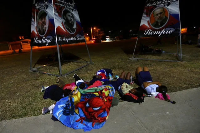 People rest on a sidewalk while waiting for the cortege carrying the ashes of Cuba's former President Fidel Castro to drive toward Santa Ifigenia cemetery in Santiago de Cuba, Cuba, December 4, 2016. (Photo by Ivan Alvarado/Reuters)