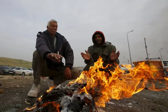 Palestinians working in Israel warm themselves by a fire as they wait to cross through the Israeli-controlled Mitar checkpoint south of the West Bank city of Hebron January 19, 2016. (Photo by Mussa Qawasma/Reuters)