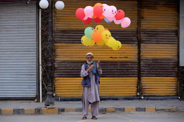 A Pakistani balloon-seller man waits for customers outside a closed market after the government ordered the closure of markets, after new cases of COVID-19 were reported across the country, in Peshawar, Pakistan, 10 May 2021. Pakistani authorities imposed smart lockdowns in an effort to curb the outbreak of a third wave of infections with Covid-19. (Photo by Arshad Arbab/EPA/EFE)
