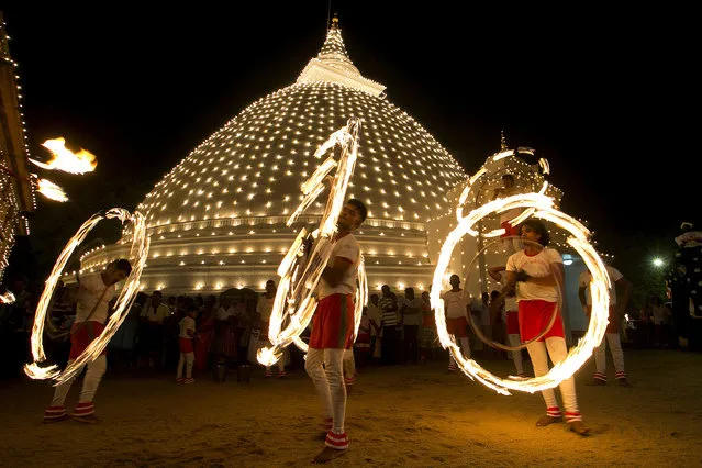 In this photo taken on January 20, 2016, Sri Lankan fireball dancers are seen performing during the inauguration of the annual 'Duruthu Perahera' festival at Kelani Buddhist temple, in the outskirts of Colombo, Sri Lanka. The festival is held to commemorate Buddha's first visit to Sri Lanka about 2500 years ago. It is widely believed that Buddha visited the island nation on three occasions, spreading his doctrine that is the foundation of Buddhism, one of the world's major faiths. (Photo by Eranga Jayawardena/AP Photo)