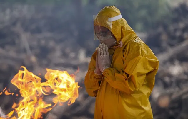 A family member prays as he performs the last rites of a person who died due to COVID-19 at a crematorium in Jammu, India, Monday, May 31, 2021. (Photo by Channi Anand/AP Photo)