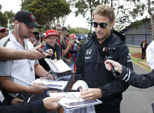 McLaren Formula One driver Jenson Button of Britain (R) signs autographs as he arrives for the first practice session of the Australian F1 Grand Prix at the Albert Park circuit in Melbourne March 13, 2015.  REUTERS/Brandon Malone