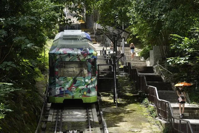 A Peak Tram passes uphill of the Victoria Peak in Hong Kong on June 16, 2021. (Photo by Vincent Yu/AP Photo)