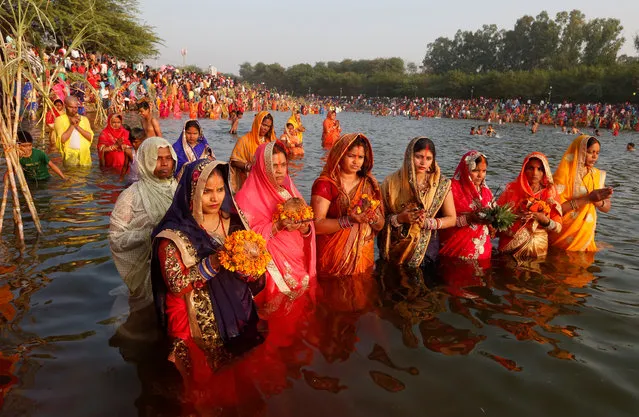 Hindu women hold offerings as they worship the Sun god in the waters of a lake during the Hindu religious festival of Chhath Puja in Chandigarh, India, India, November 13, 2018. (Photo by Ajay Verma/Reuters)