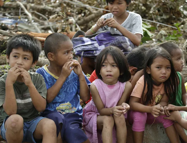 Children who say they fled when armed men were seen in their village eat bread while waiting in Tacloban city, Leyte province in central Philippines Wednesday, November 13, 2013. Five days after one of the strongest tropical storms on record leveled tens of thousands of houses in the central Philippines, relief operations were only starting to pick up pace, with two more airports in the region reopening, allowing for more aid flights. (Photo by Bullit Marquez/AP Photo)
