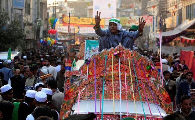 A boy gestures from the top of a vehicle as he takes part in a religious procession during celebration to mark Eid-e-Milad-ul-Nabi, the birthday anniversary of Prophet Mohammad, in Rawalpindi, Pakistan December 12, 2016. (Photo by Faisal Mahmood/Reuters)