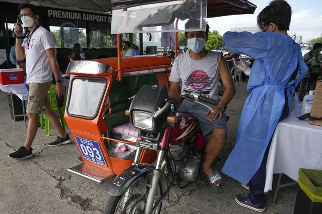 A pedicab driver is inoculated with China's Sinovac COVID-19 Vaccine in Manila, Philippines on Tuesday, June 22, 2021, in Manila, Philippines. The Philippine president has threatened to order the arrest of Filipinos who refuse the COVID-19 vaccination and told them to leave the country for hard-hit countries like India and the United States if they would not cooperate with massive efforts to end the pandemic. (Photo by Aaron Favila/AP Photo)